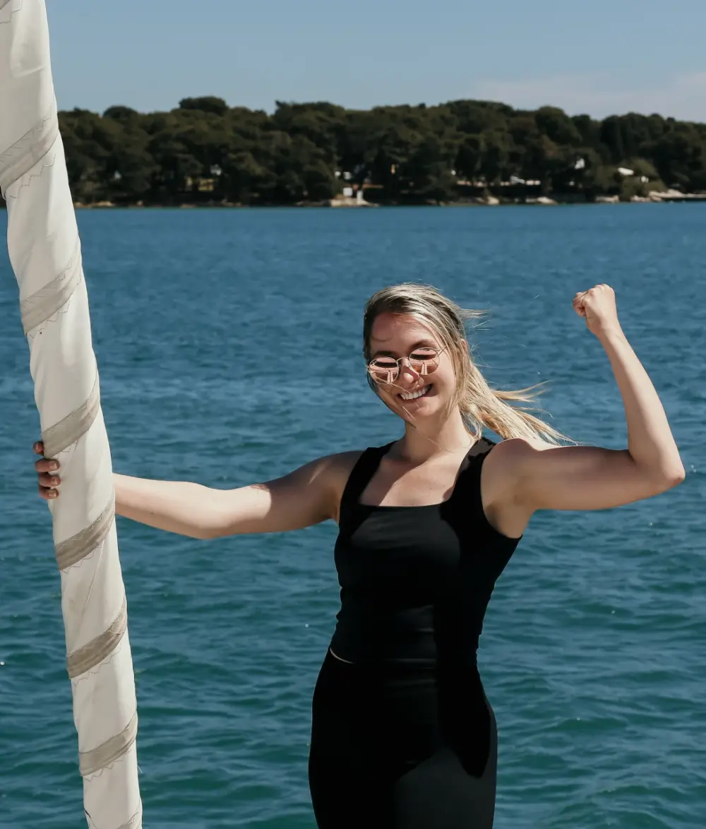 Manuela Nicolic am Segelboot, sie zeigt ihren Bizepts und lacht in die Kamera