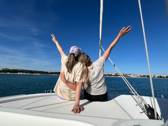 Zwei Frauen am Bug des Segelbootes. Die Hände in Höhe gestreckt. Bereit für Abenteuer.