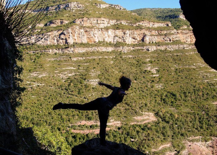 Jemand macht Yoga am Berg auf einem Felsvorsprung