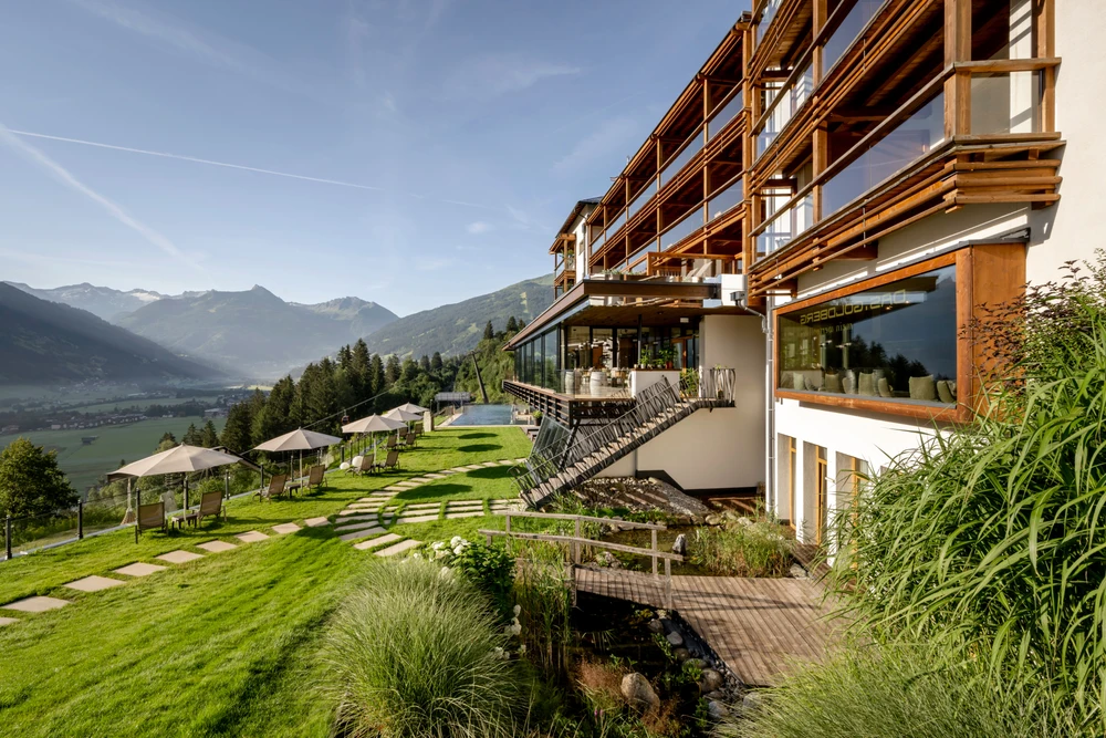 Aussenansicht des Hotels, umgeben von Bergen und grüner Landschaft