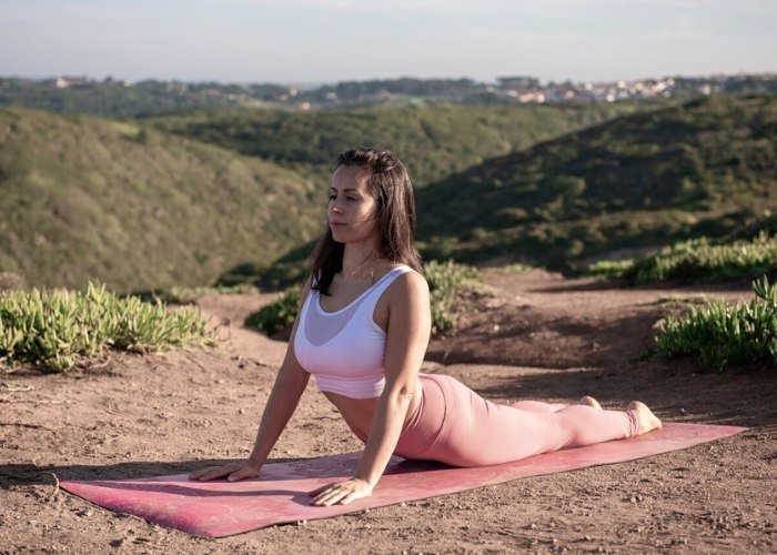 Eine junge Frau praktiziert Yoga in der Wüstenlandschaft.
