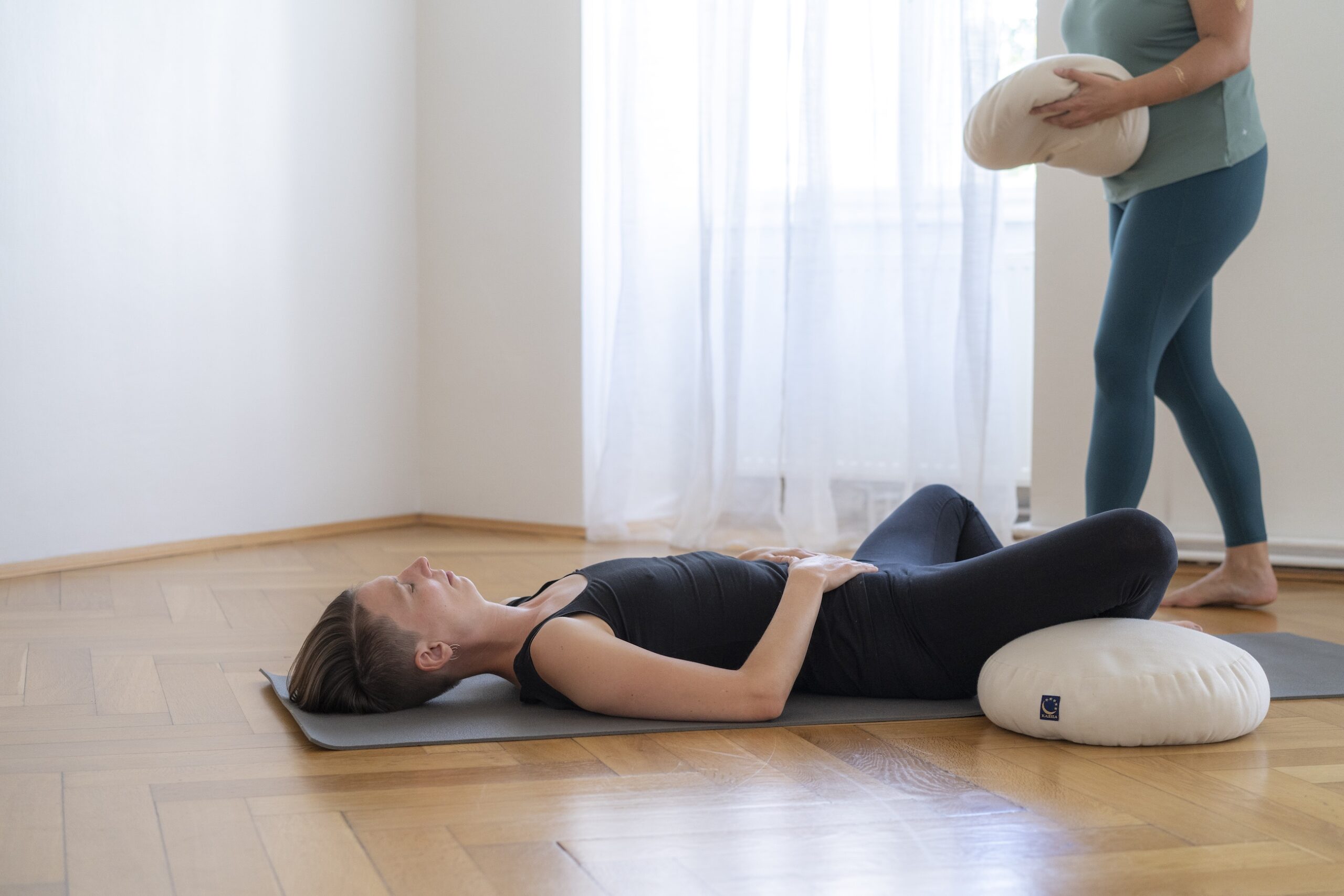 mayogi manu trägt Yogakissen zu Teilnehmerin